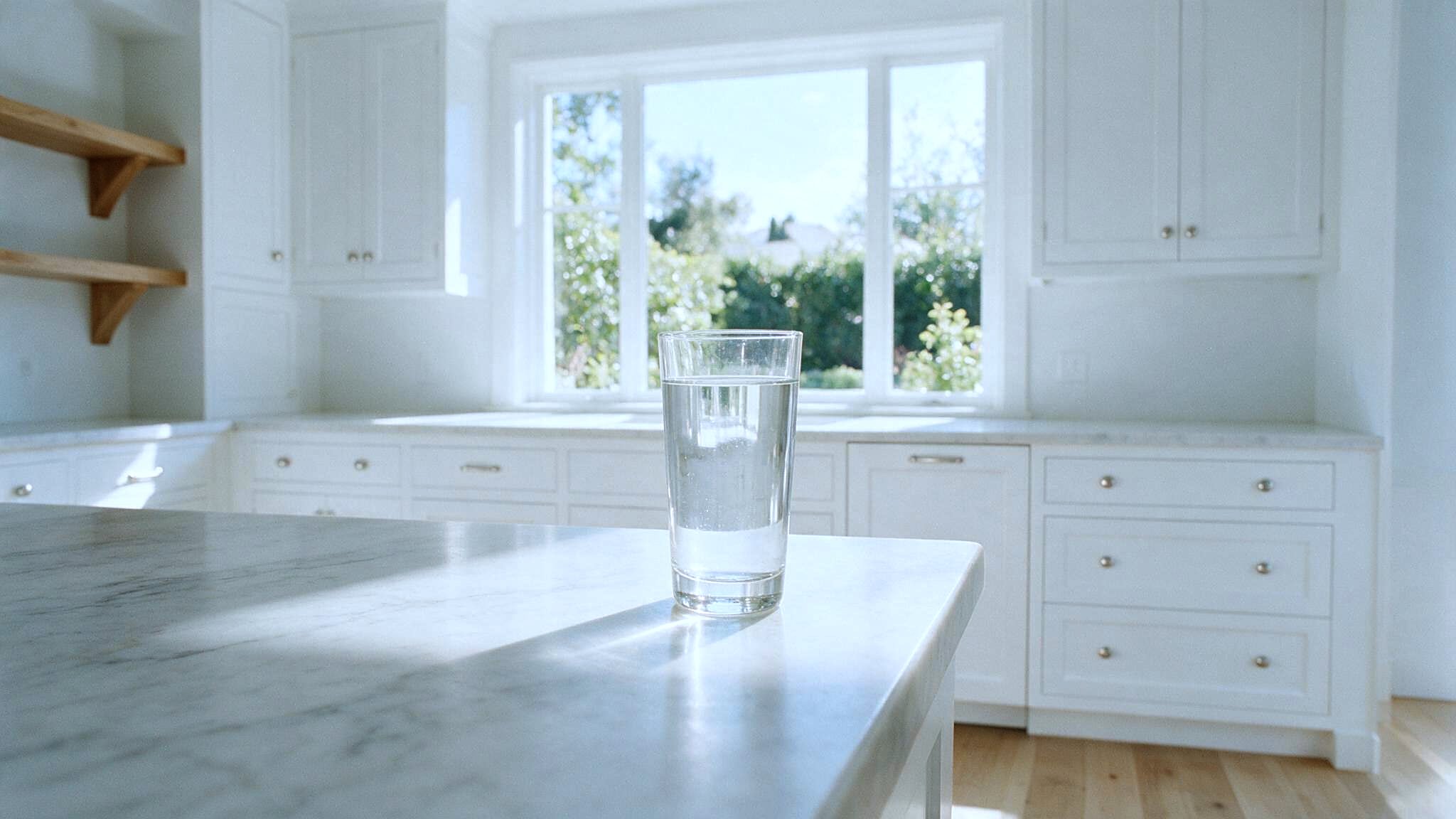 A glass of water on the counter of a bright kitchen